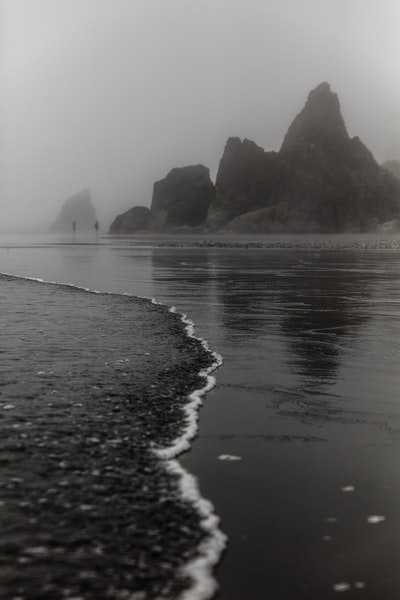 两个人站在岩层前的灰度照片